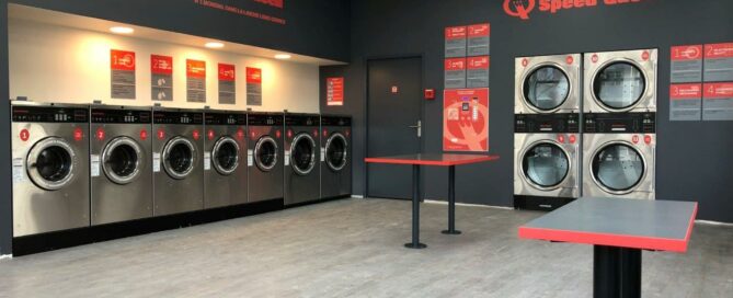 A Speed Queen Commercial Laundry room featuring several washing machines and a countertop for folding clothes.