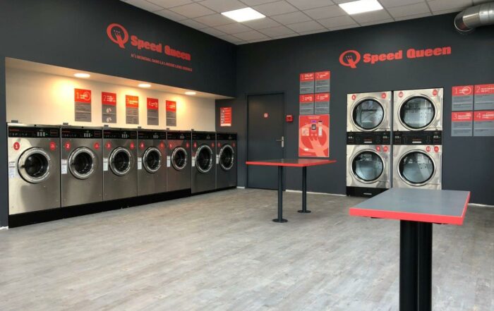 A Speed Queen Commercial Laundry room featuring several washing machines and a countertop for folding clothes.
