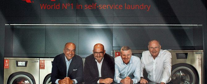 Four people posing in front of the camera in a Speed Queen laundry.
