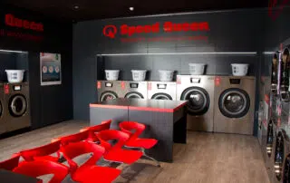 A laundry room featuring red chairs and several washing machines, creating a vibrant and functional space for laundry tasks.
