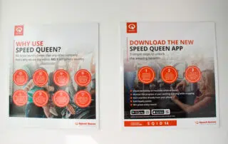 Two posters on a wall promoting the new Speed Queen app with the message "Download the new Speed Queen app.